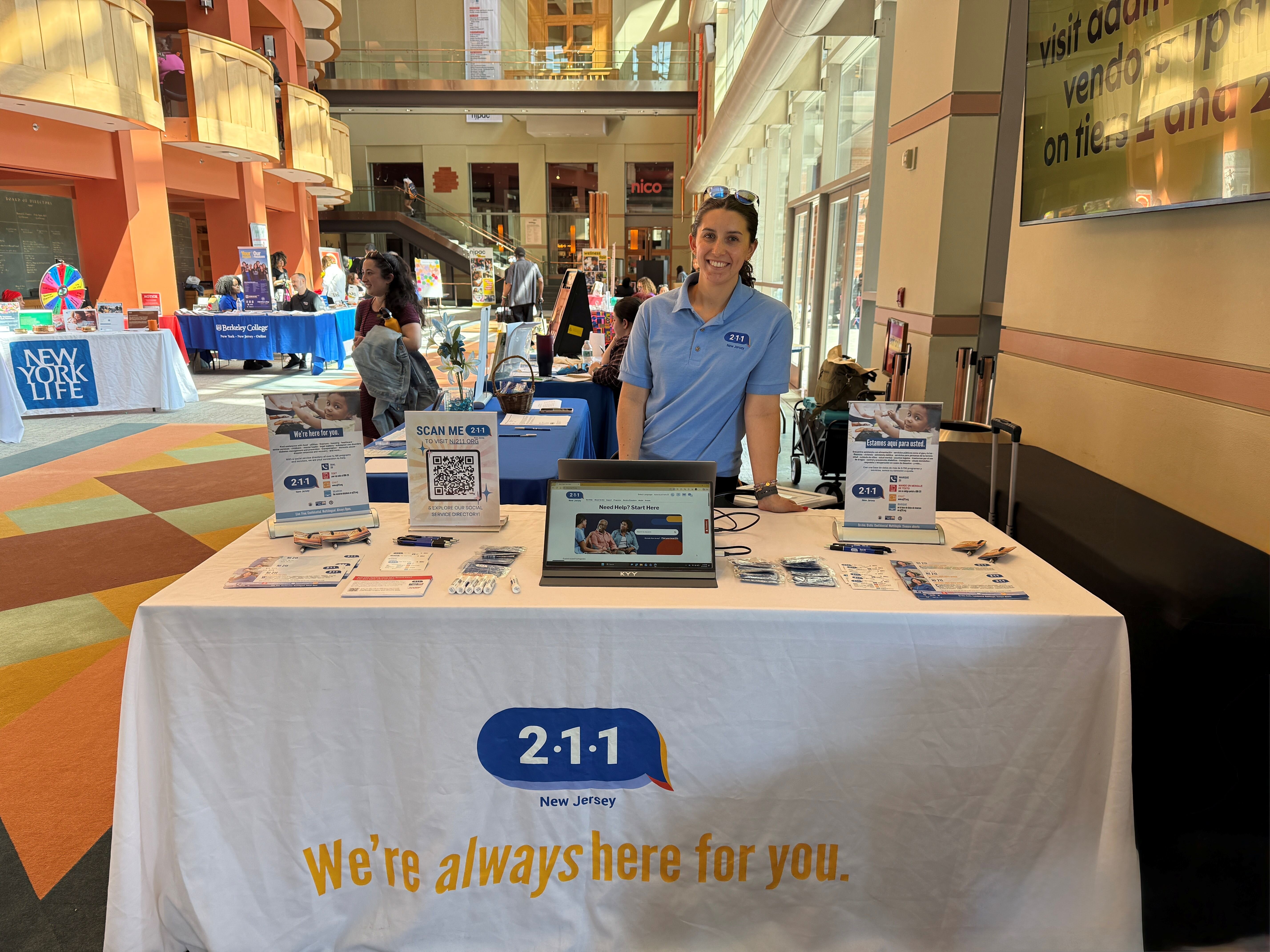 woman stand behind info table